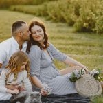 Family enjoying a joyful picnic in a sunny field with their pet cat, capturing a serene and loving moment.